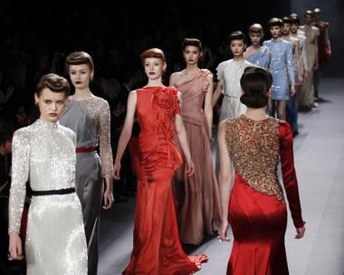 In den Kollektionen von Jenny Packham finden sich ausschließlich lange Roben und schicke Kleider, die aber auch im Alltag getragen werden können Bild Laufsteg mit Models in Abendgarderobe